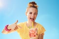 Smiling woman against blue sky pointing at refreshing cocktail Royalty Free Stock Photo