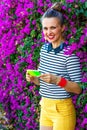 Smiling woman against colorful magenta flowers bed writing sms Royalty Free Stock Photo