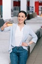 smiling woman akimbo showing credit card in hand in furniture store