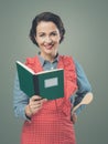 Smiling woman in apron with cookbook