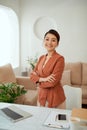 Smiling woman with arms crossed stands at her workplace in home office Royalty Free Stock Photo