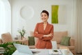 Smiling woman with arms crossed stands at her workplace in home office Royalty Free Stock Photo