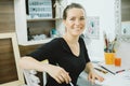 Smiling woman artist with paintbrush at the workplace