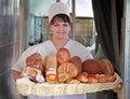 Smiling Woman baker with bread products in bakery