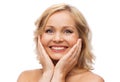 Smiling woman with bare shoulders touching face