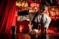 smiling woman bartender gently pours cocktail from shaker into glass at bar counter