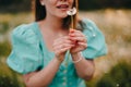 Smiling woman beautiful blowing on ripened dandelion in park. Girl in retro turquoise dress enjoying summer in Royalty Free Stock Photo