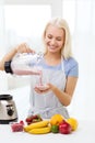 Smiling woman with blender preparing shake at home Royalty Free Stock Photo