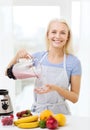 Smiling woman with blender preparing shake at home Royalty Free Stock Photo