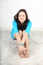 Smiling woman in blue dress sits on soft carpet Royalty Free Stock Photo