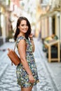 Smiling woman with blue eyes with brown wavy hair outdoors. Girl wearing flower dress in urban background. Beauty and Royalty Free Stock Photo