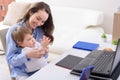 Smiling woman in blue shirt with child sitting at laptop playing palm games, happy motherhood, remote work at home with children Royalty Free Stock Photo