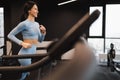 Smiling woman in blue sportsuit is exercising on treadmill. Body care concept.