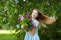 Beautiful woman in a blue summer dress with lilac flowers in a blooming garden. Spring Blossom Royalty Free Stock Photo