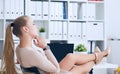 Side view of smiling woman boss relaxing and holding legs on office desk. Royalty Free Stock Photo