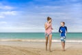 Smiling woman and boy running together on a beautiful beach on vacation Royalty Free Stock Photo