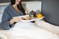 Smiling woman brunette holding breakfast tray with tea cup,cake and fruits in bed at home in the bedroom Royalty Free Stock Photo