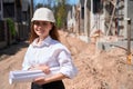 Smiling woman building engineer standing at construction site with blueprint Royalty Free Stock Photo