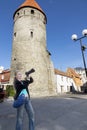 The smiling woman with the camera photographs old city wall towers. Tallinn, Estonia