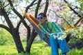 Smiling woman in carnival sunglasses is relaxing in a hammock