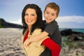 Smiling woman carries the child on her back on the beach \