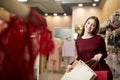 Smiling woman carrying some shopping bags with lingerie store showcase on the background. Pretty smiling caucasian girl