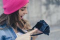 Smiling woman in casual clothes and pink hat holding camera and showing good shot she made during the street photo shooting. Close Royalty Free Stock Photo