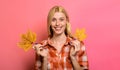Smiling woman in casual clothes with yellow maple leaves. Autumnal mood. Happy girl in plaid shirt.