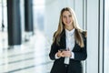 Smiling business woman standing in office with mobile phone in hand looking at camera Royalty Free Stock Photo