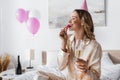 Smiling woman with champagne eating macaroon