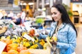 Smiling woman checks on pumpkins offered for sale in the grocery store Royalty Free Stock Photo