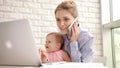 Smiling woman with child speaking phone. Happy business mother working at home