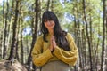 Smiling woman clasping hands while looking at camera outdoors