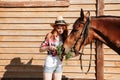 Smiling woman cowgirl giving fresh grass ti her horse Royalty Free Stock Photo