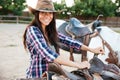 Smiling woman cowgirl standing and preparing saddle for riding horse Royalty Free Stock Photo