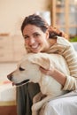 Smiling Woman Cuddling with Dog on Bed in Sunlight Royalty Free Stock Photo