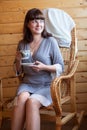 Smiling woman with a cup of coffee, portrait indoor, female sitting on a rattan chair