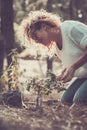Smiling woman with curly hair planting new tree in forest or garden. Happy woman taking care of plant in nature. Woman celebrating Royalty Free Stock Photo
