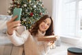 Dark-haired woman near christmas tree making photos