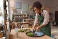 Smiling woman decorator making green ikebana on tray with epoxy resin in florist workshop