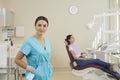 Smiling woman doctor dentist looking at camera over sitting woman patient at background Royalty Free Stock Photo