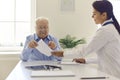 Smiling woman doctor giving paper prescription to elderly man patient in clinic Royalty Free Stock Photo