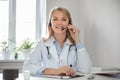A smiling woman doctor with headphones and a microphone in a white coat conducts an online consultation. Ehealth Royalty Free Stock Photo