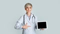 Smiling woman doctor points finger at tablet with blank screen