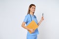 Smiling woman doctor raising pen up and holding clipboard, standing in uniform isolated over white background Royalty Free Stock Photo