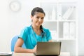 Smiling woman doctor sitting at desk in medical office Royalty Free Stock Photo