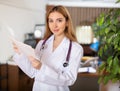 Smiling woman doctor standing in office with papers in hands Royalty Free Stock Photo