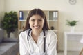 Smiling woman doctor therapist sitting and looking at camera in medical clinic office Royalty Free Stock Photo