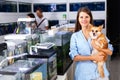 Smiling woman with dog standing near small aquarium with fish Royalty Free Stock Photo