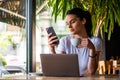 Smiling woman drinking coffee and using her mobile phone. Satisfied female enjoying cup of coffee. Close up portrait of beautiful Royalty Free Stock Photo